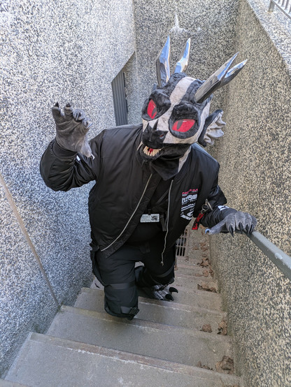 Me wearing lizard cosplay walking up stairs from somewhere underground, trying to look scary.